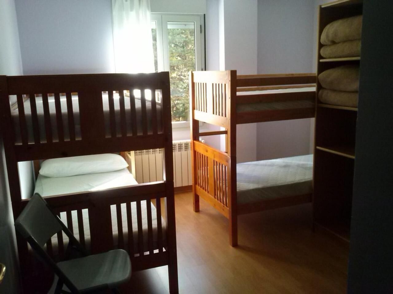 Una habitación con literas, una silla y un radiador.