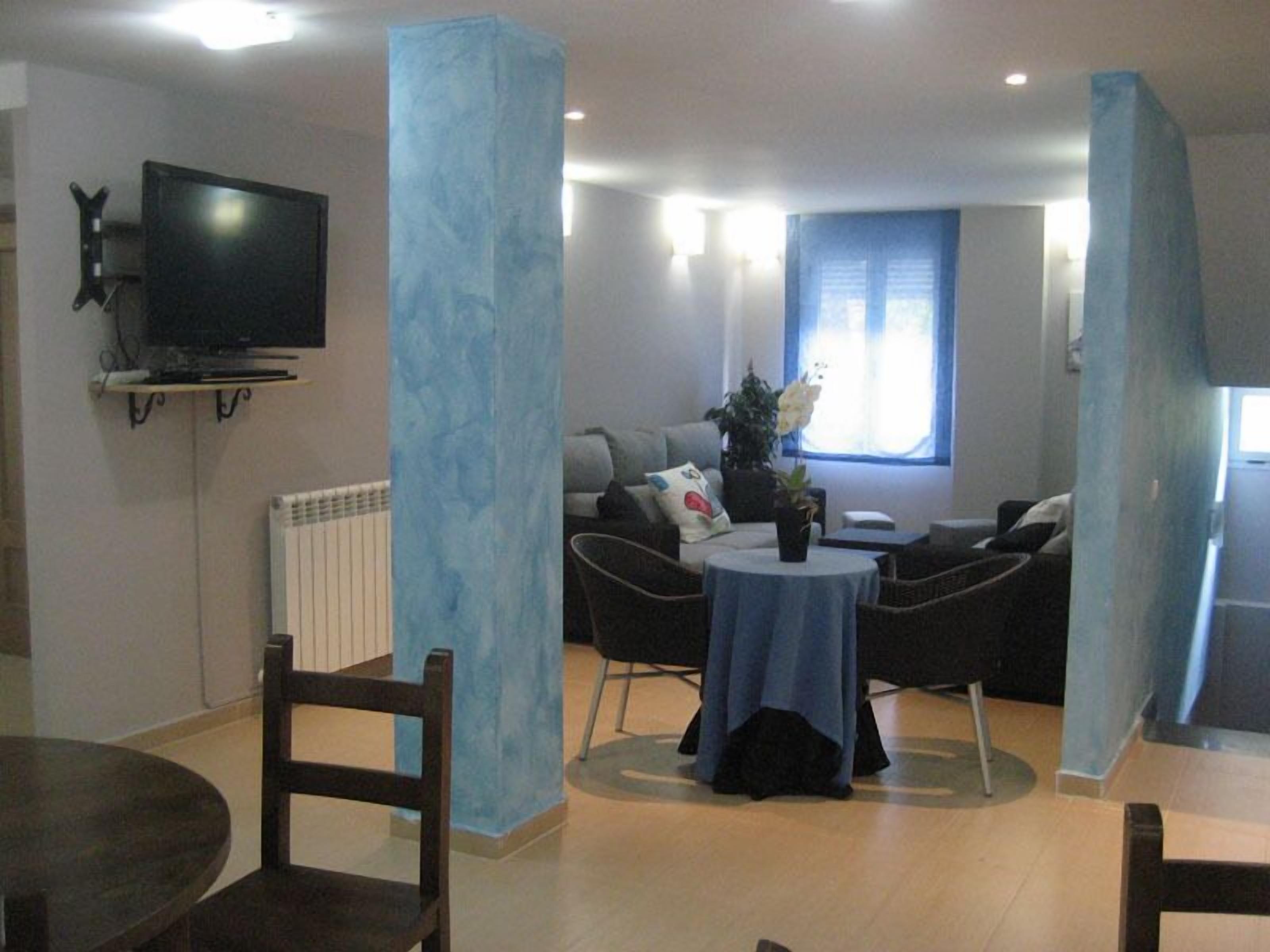 Un salon moderne doté d’un téléviseur à écran plat, d’un canapé, d’une table basse et d’un coin repas avec des chaises.
