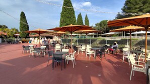 An outdoor patio with tables and chairs, umbrellas, and a fence. - La Manne - Bormes les Mimosas (Bormes-Les-Mimosas)