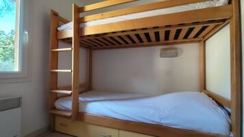 A bunk bed with a ladder, a small shelf, and a window.