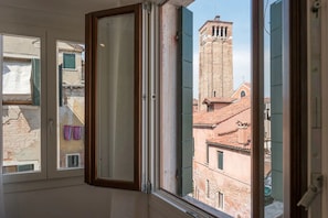 A room with a large window overlooking a historic building with a bell tower.