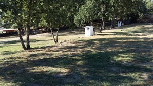 A grassy outdoor area with trees and a small white structure, possibly a utility shed. - Las Casitas de Las Arribes (Aldeadavila de la Ribera)