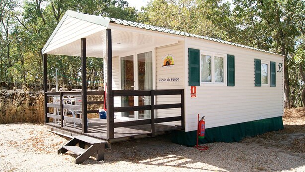 A small, single-story mobile home with a covered porch and a fire extinguisher outside. - Las Casitas de Las Arribes (Aldeadavila de la Ribera)