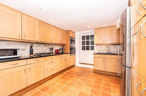 A modern kitchen with wooden cabinets, a stainless steel refrigerator, a microwave, and a gas stove.
