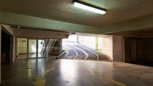 Un parking souterrain vide, avec une rampe incurvée menant à un escalier.