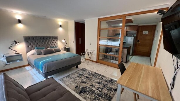 Une chambre à coucher avec un lit, des tables de chevet, un bureau et un téléviseur.