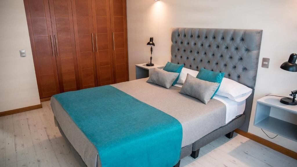 Un dormitorio con una cama grande, un armario y lámparas de noche.