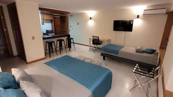 A room with a bed, a desk, a chair, and a TV.