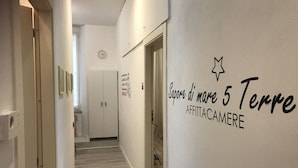 A hallway with a wooden floor, white walls, and a door at the end. There is a wall sign that reads "Sapore di mare 5 Terre" and "AFFITTACAMERE". - Sapore di mare 5 Terre Affittacamere (La Spezia)