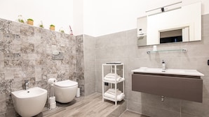 A modern bathroom with a bidet, a sink, and a glass shelf with towels. - Sapore di mare 5 Terre Affittacamere (La Spezia)