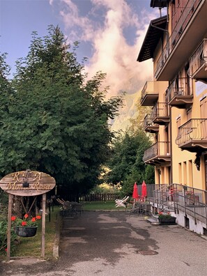 Een straat met een houten bord, een gebouw met balkons en een berg op de achtergrond.