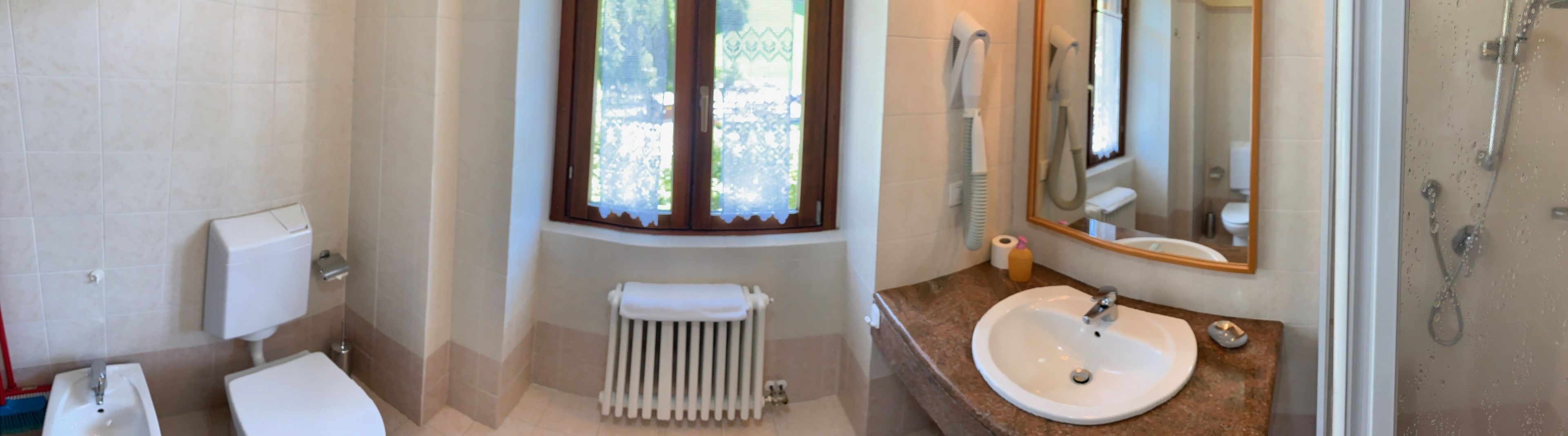 Un baño con inodoro, lavabo, espejo y ducha.