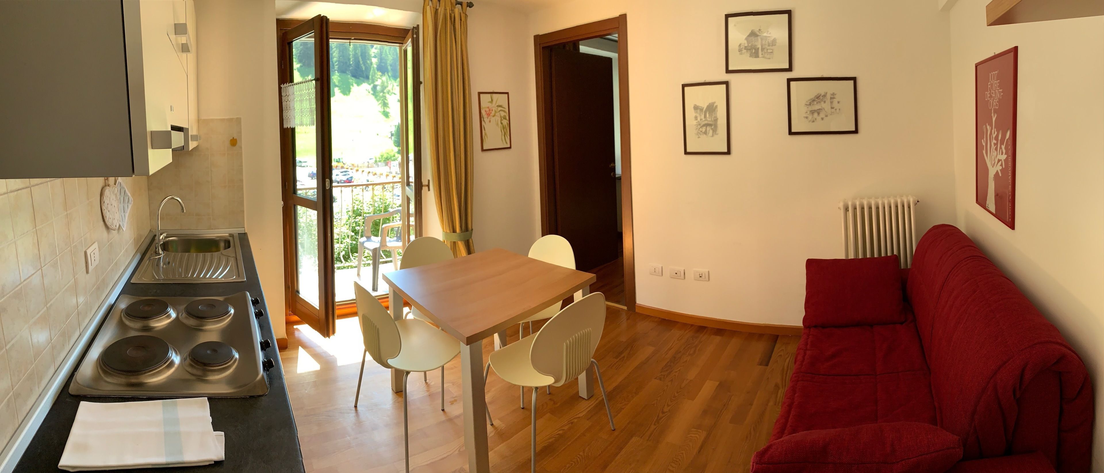 A compact living space with a kitchenette, dining area, and a red sofa.