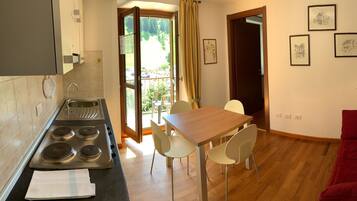 A compact living space with a kitchenette, dining area, and a red sofa.