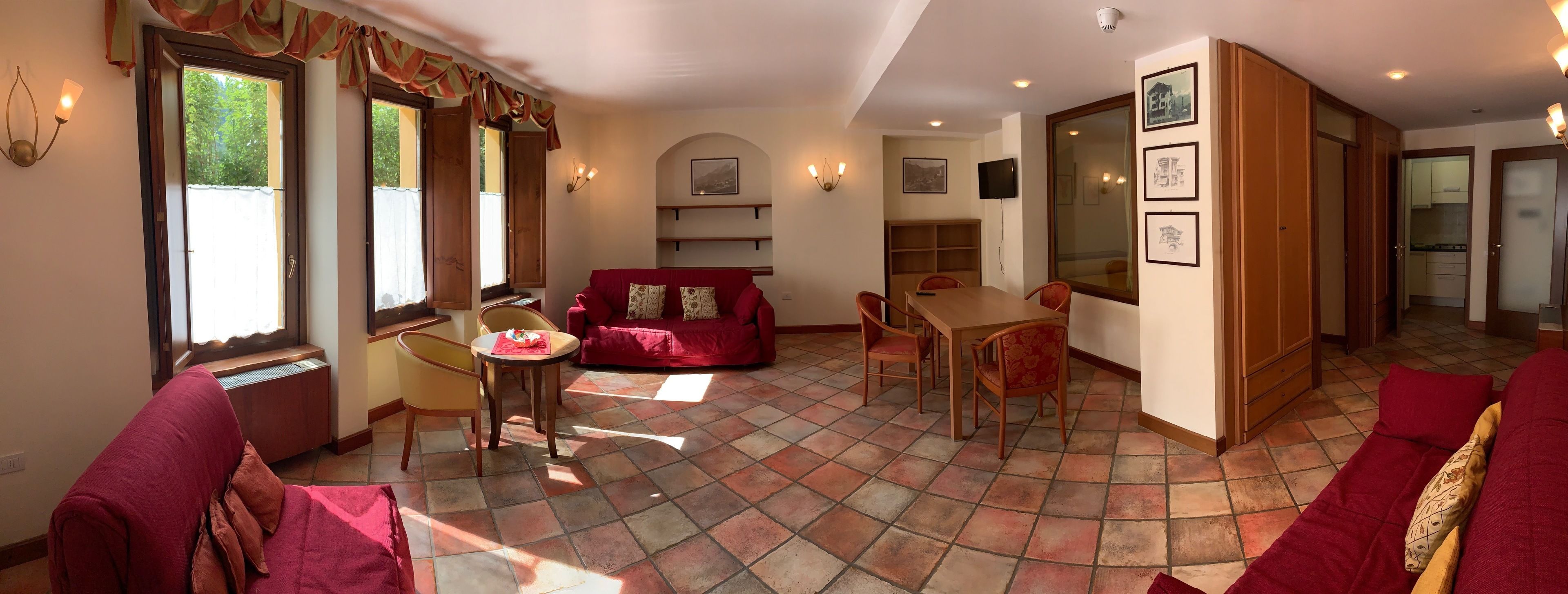 Un amplio salón con un sofá rojo, una mesa de comedor y una cocina al fondo.