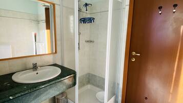 A bathroom with a sink, mirror, shower, and toilet.