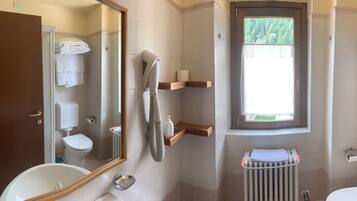 A bathroom with a toilet, sink, mirror, towel rack, and a window.
