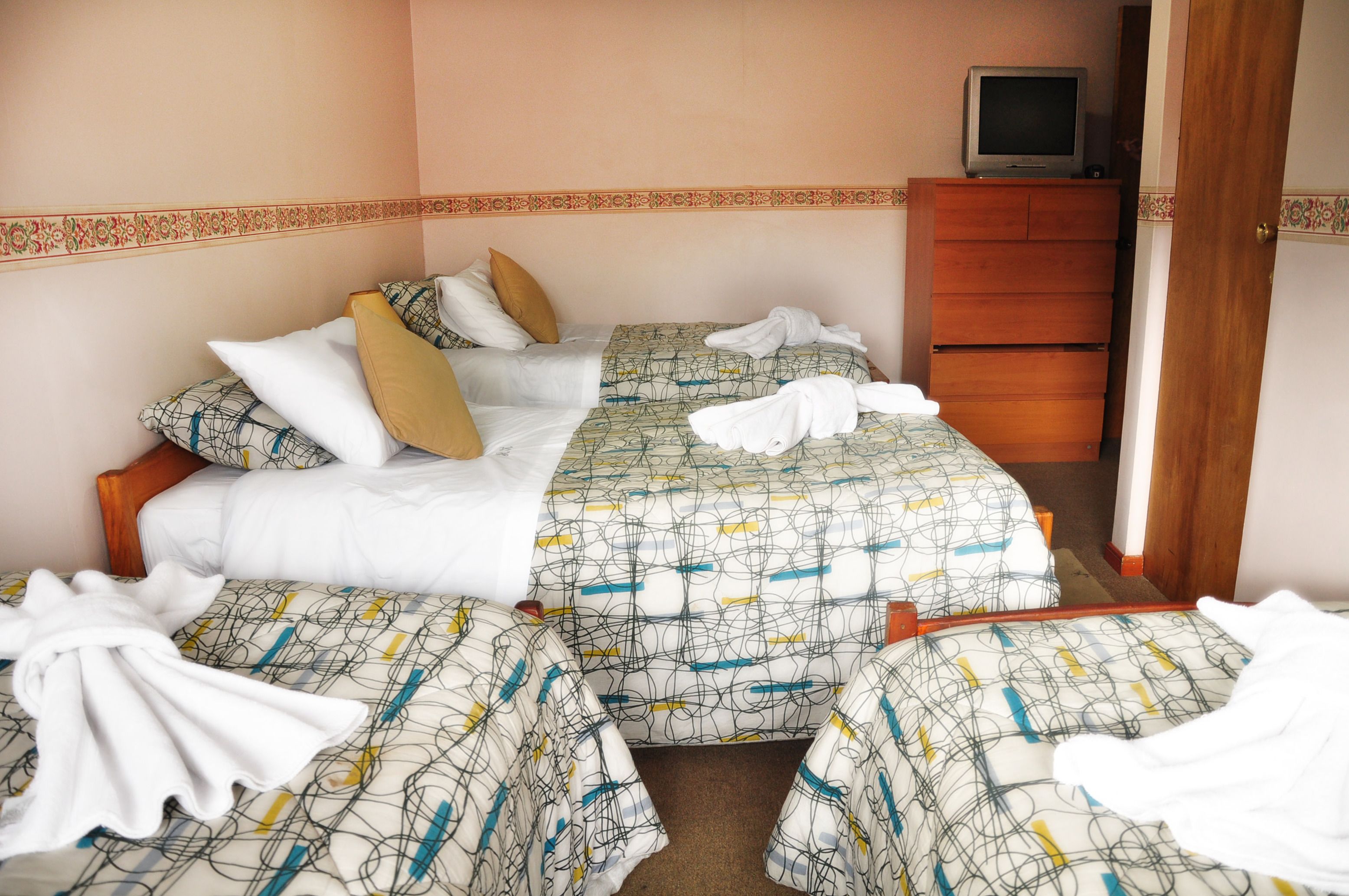 Ett hotellrum med två sängar, en tv på en byrå och en spegel.