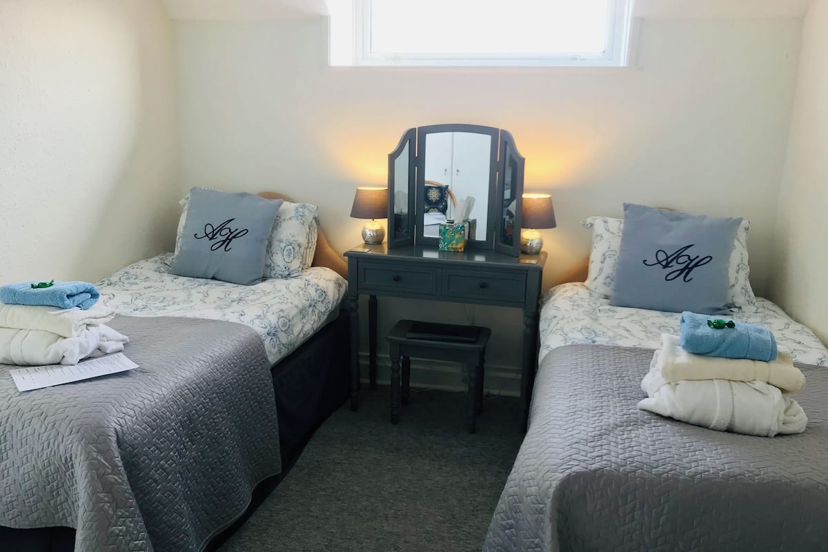 A twin bedroom with two beds, a desk, a chair, and a window.