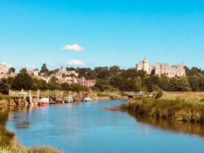 A river with boats, a castle on a hill, and a town in the background. - Arden House (Arundel)