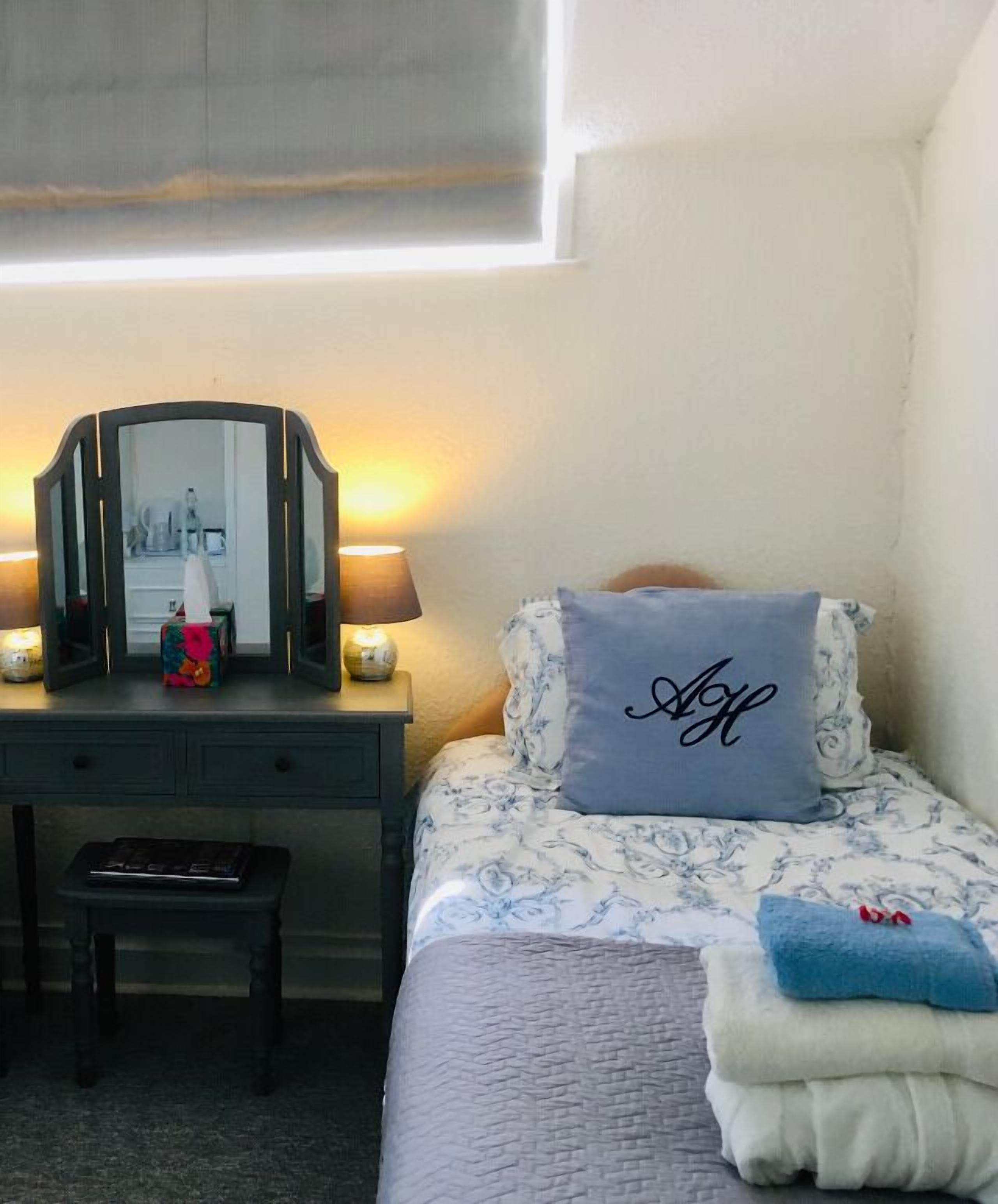 Une chambre à coucher avec un lit, une table de chevet, un miroir et une lampe.