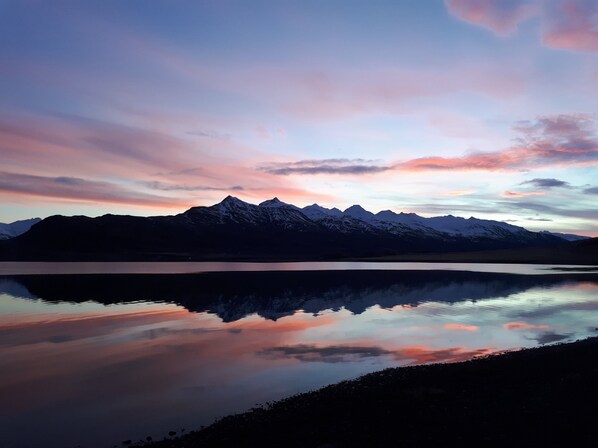 A mountain range reflected in a calm lake at sunset.