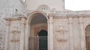 Un edificio histórico con una gran entrada en arco, columnas ornamentales y una puerta con reja.