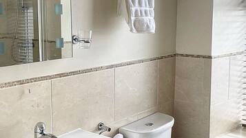 A bathroom with a sink, toilet, and a towel rack with rolled towels.