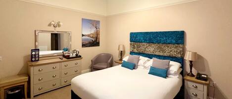 A bedroom with a large bed, a dresser, a chair, a nightstand, a lamp, and a painting on the wall.