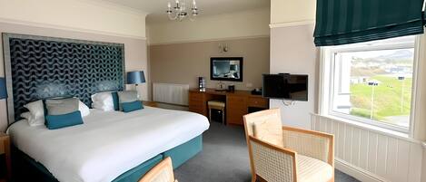 Quarto de hotel com uma cama grande, uma escrivaninha, uma televisão e vista para o exterior.