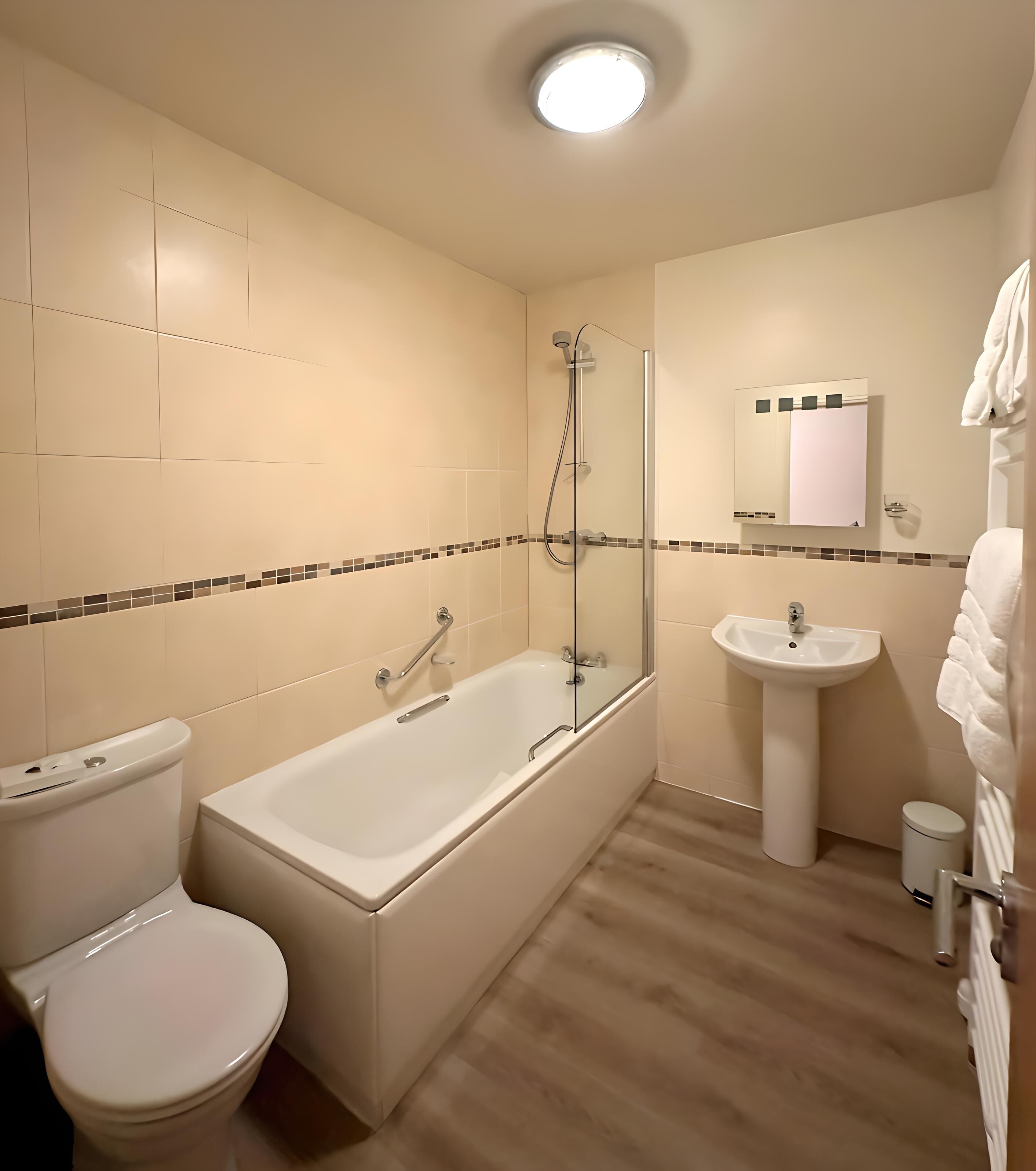 A bathroom with a bathtub, toilet, sink, and a mirror.