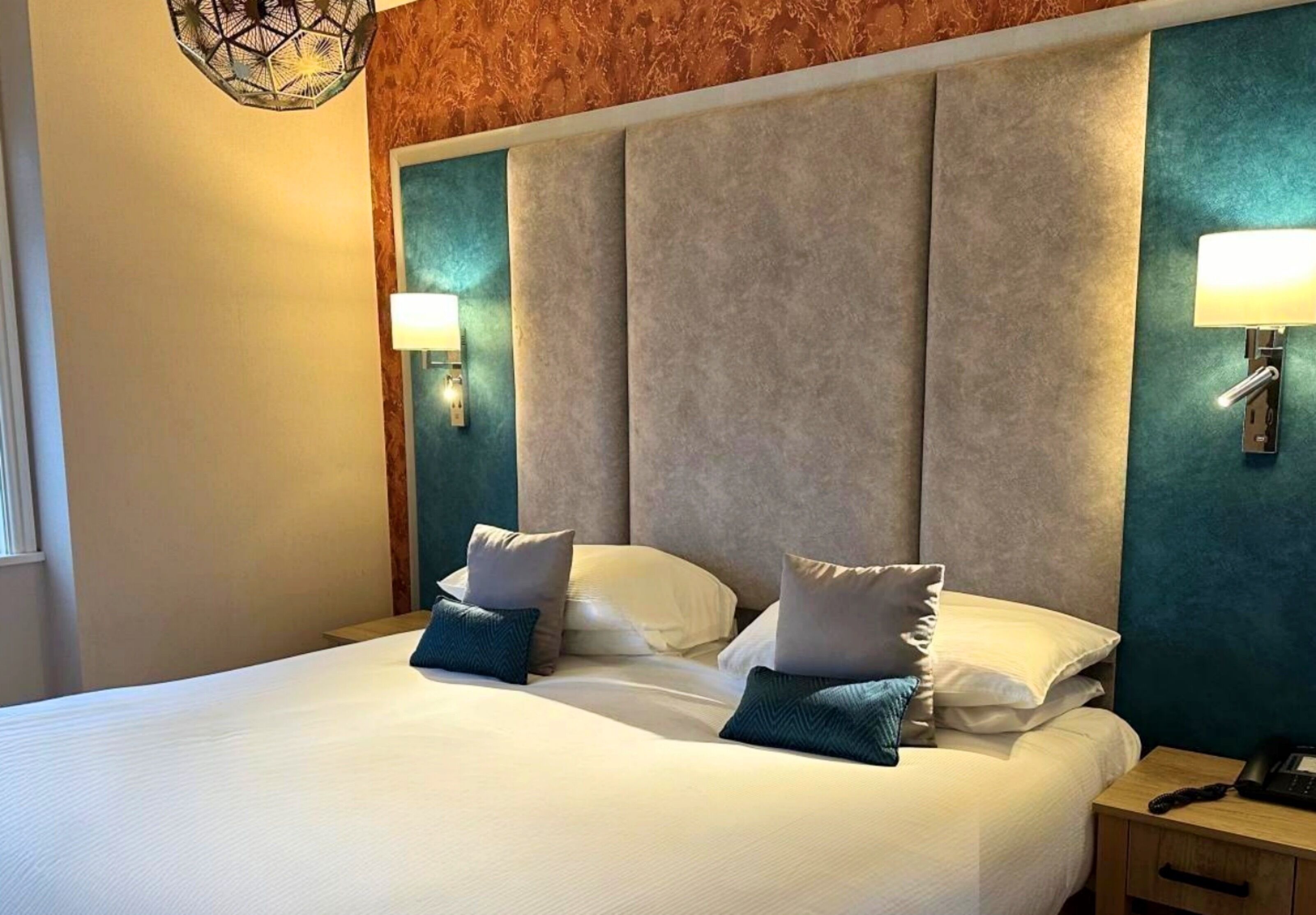 A hotel room with a large bed, two bedside tables, and a wall-mounted lamp.