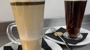 Dos vasos de bebidas sobre platos blancos con servilletas negras y una cuchara.