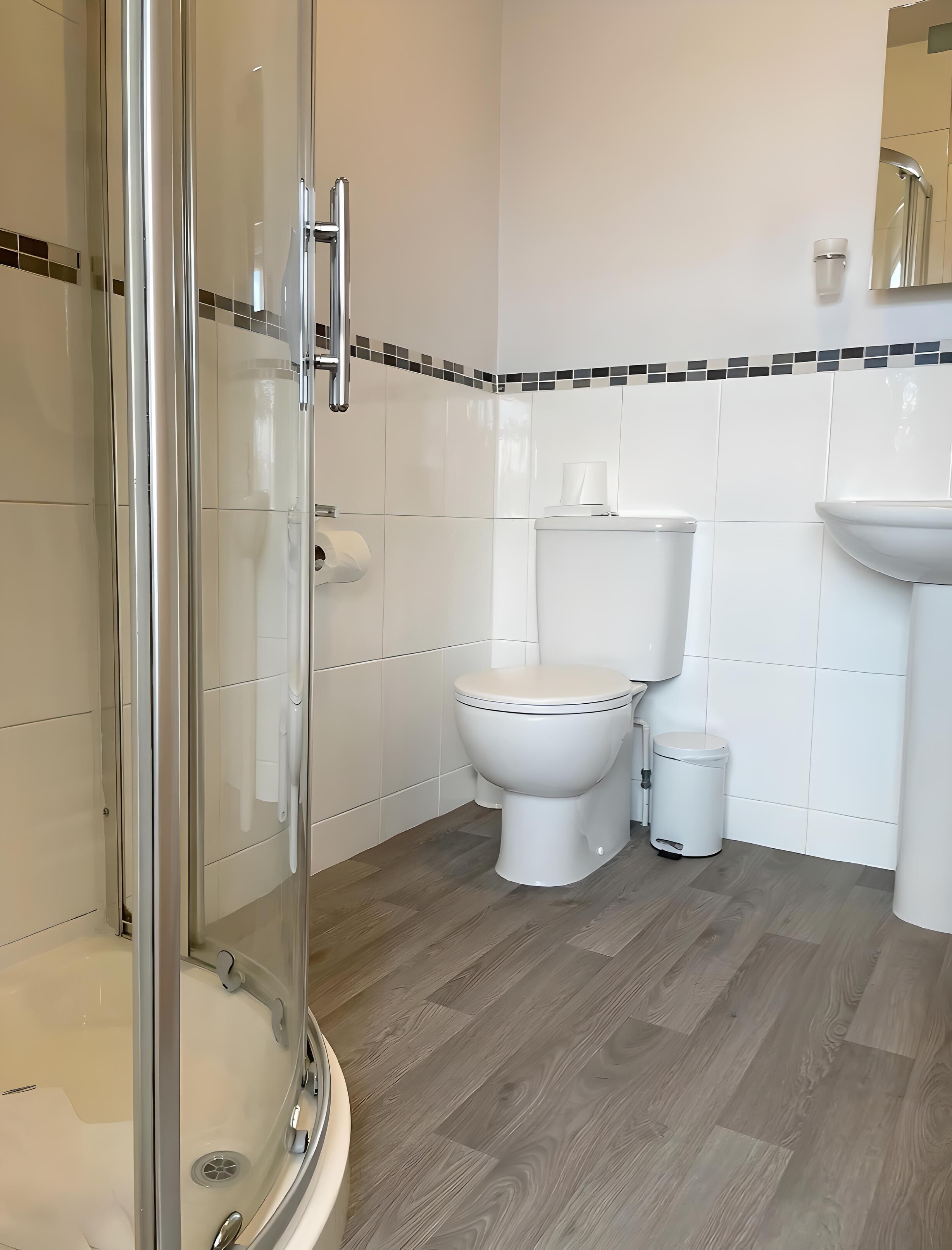 A modern bathroom with a glass-enclosed shower, a toilet, and a sink.