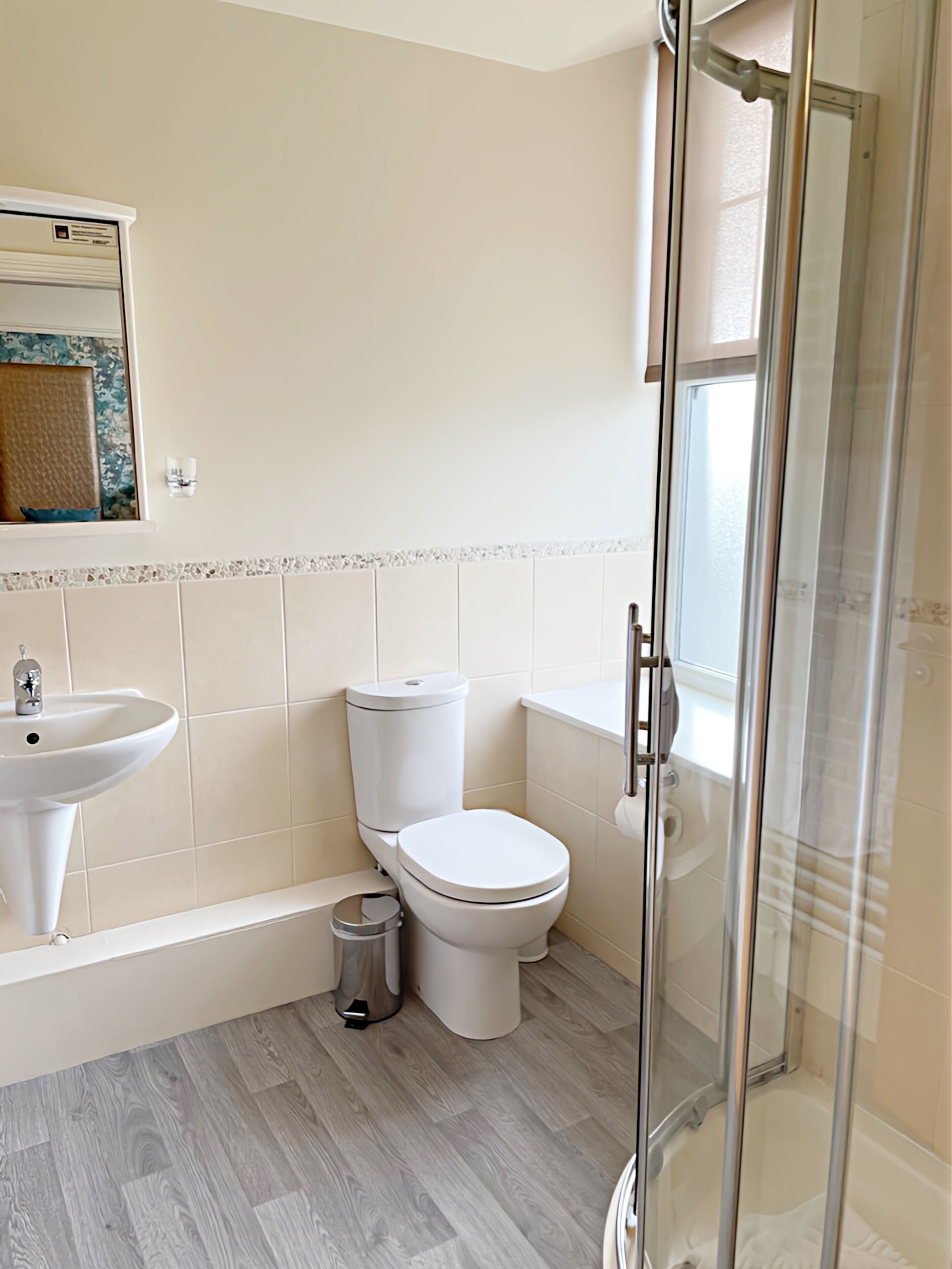 A modern bathroom with a toilet, sink, and glass-enclosed shower.