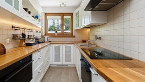 Una cocina moderna con armarios blancos, encimera de madera y una ventana que deja entrar luz natural.