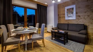 Una sala moderna con una mesa de comedor redonda, sofás grises y una pared de acento de madera.