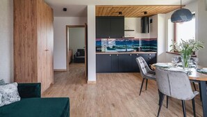 Et moderne køkken med mørke skabe, trælofter og et spiseområde med et bord dækket til to.