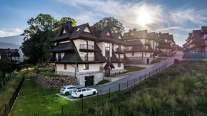Een rij traditionele huizen met steile daken, een stenen muur en een verharde oprit.