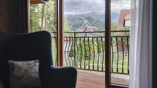 Et værelse med udsigt over et bjerglandskab fra en balkon med gelænder.