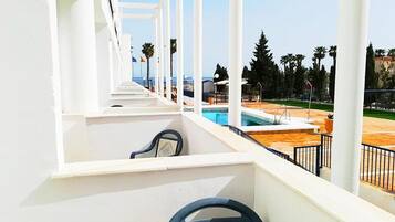 Un balcón con vista a una piscina y palmeras.