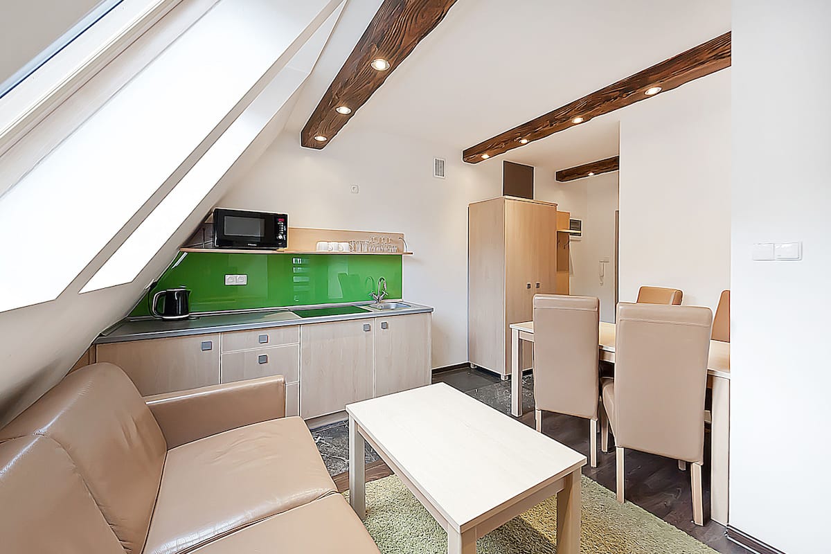 Een compacte keuken met een groen aanrecht, een magnetron en een spoelbak. Er is een eethoek met een tafel en stoelen.