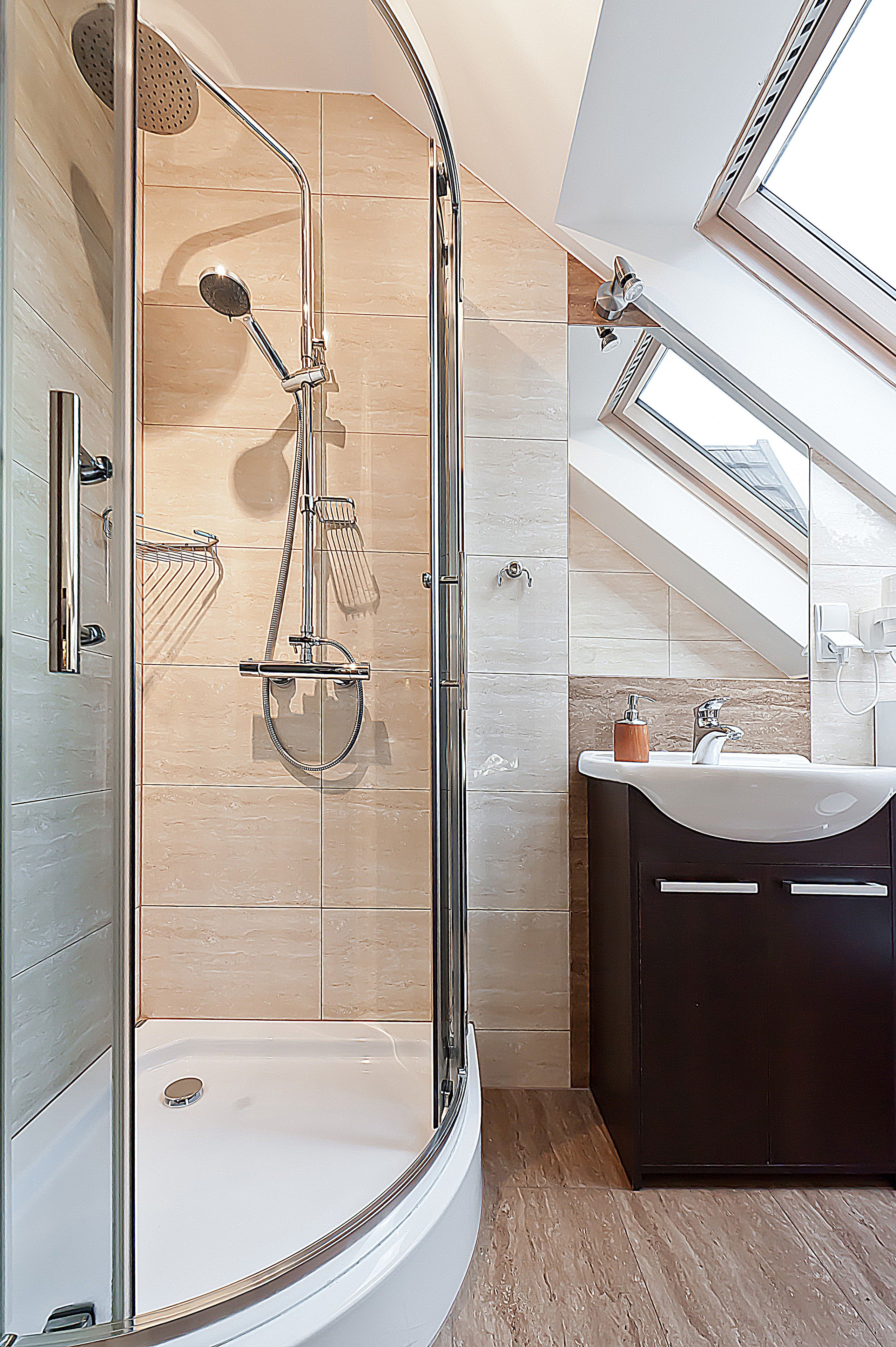 Un baño moderno con ducha acristalada, lavabo y tocador de tonos oscuros.
