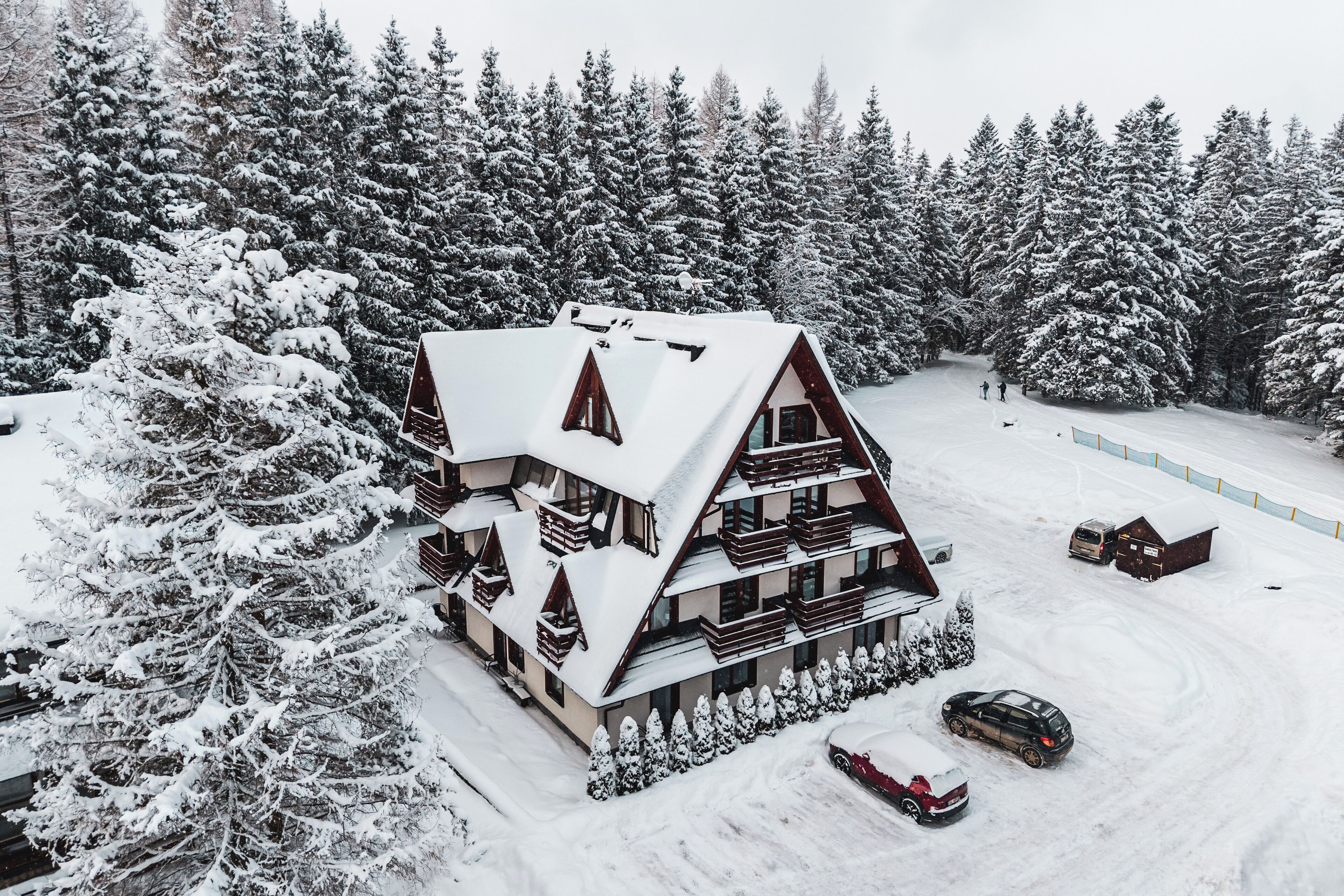 Una cabaña de varios pisos con un techo pronunciado, rodeada de árboles cubiertos de nieve.