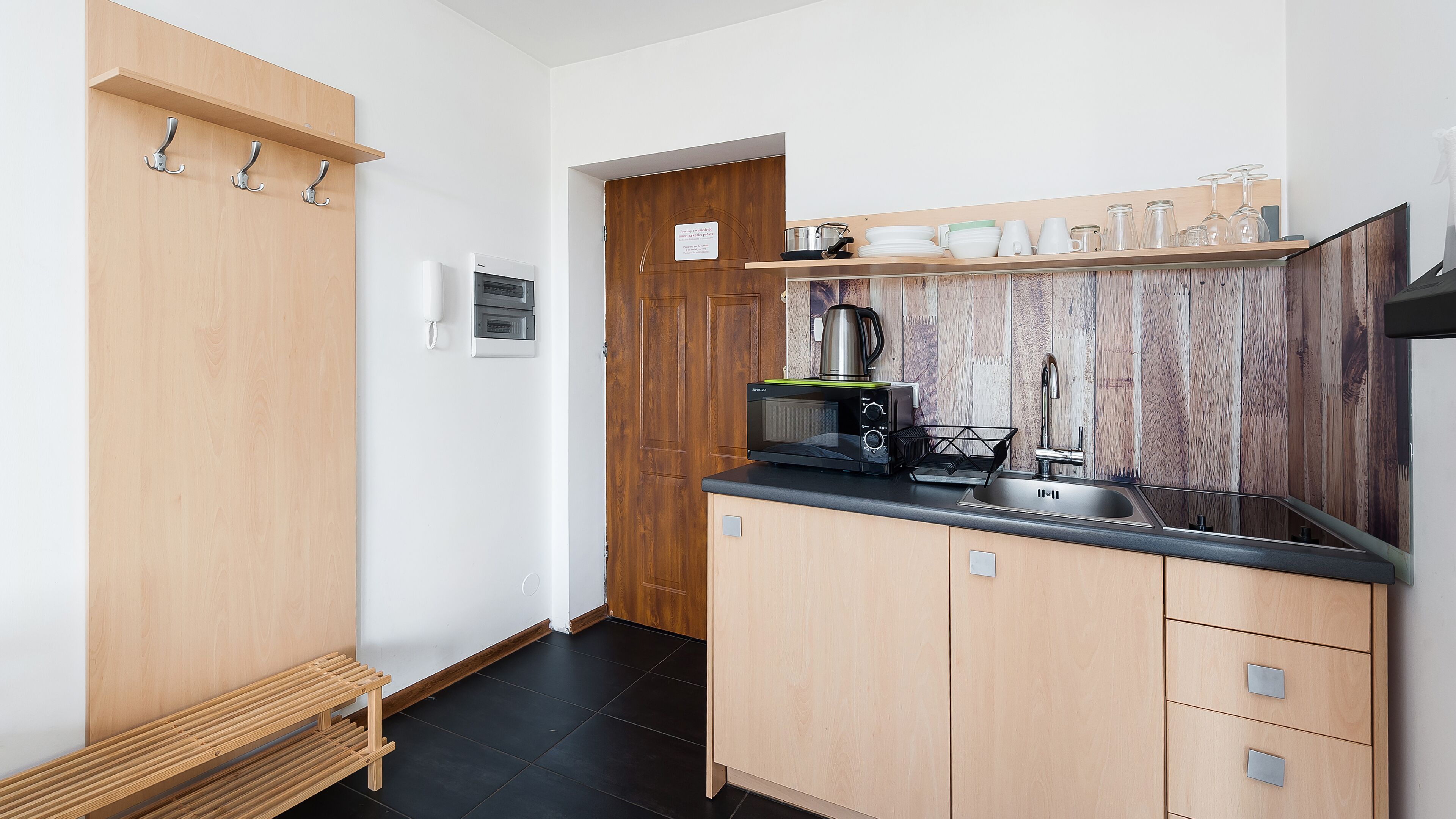 Una cucina compatta con mobili in legno, un piano di lavoro nero e un piano cottura integrato.