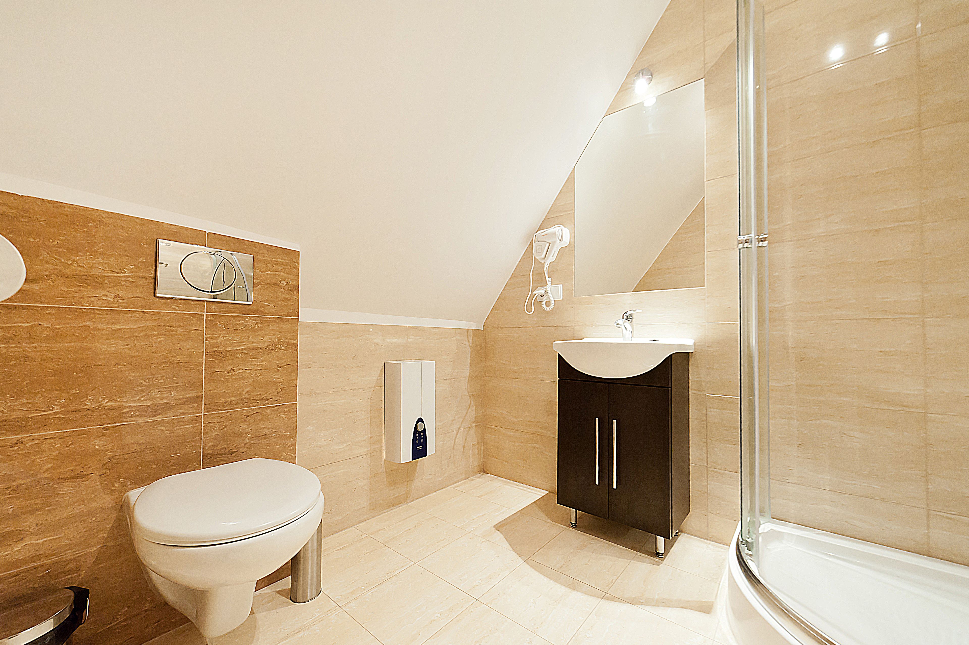 A modern bathroom with a toilet, a sink, a shower, and a mirror.