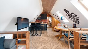 Moderni loft-tyylinen asunto, jossa on keittiö, ruokailutila ja seinälle asennettu televisio.