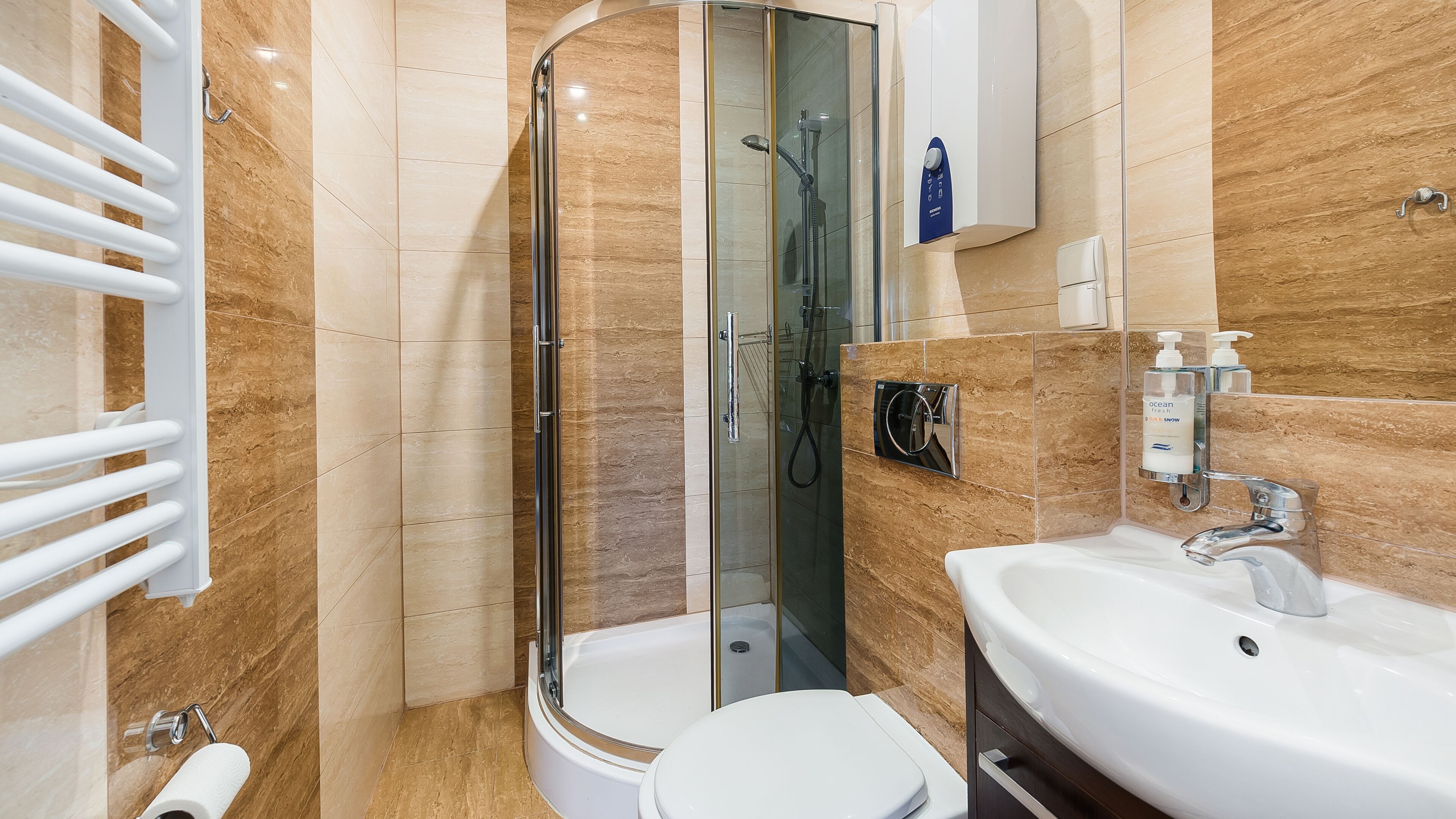 A modern bathroom with a glass-enclosed shower, a white toilet, and a sink with a mirror.