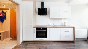 A modern kitchen with white cabinets, a black range hood, and a built-in oven. - Apartamenty Sun & Snow Poronin (Bialy Dunajec)