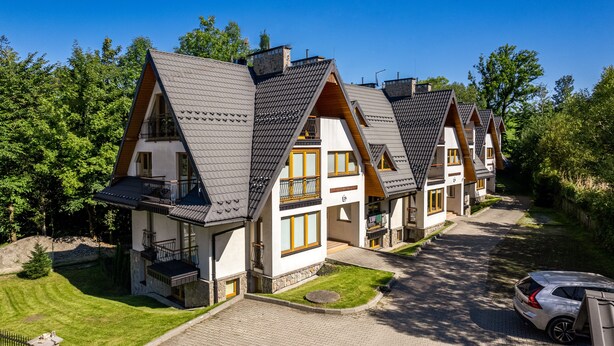 A row of modern, two-story houses with steeply pitched roofs, stone foundations, and large windows. - Apartamenty Sun & Snow Poronin (Bialy Dunajec)
